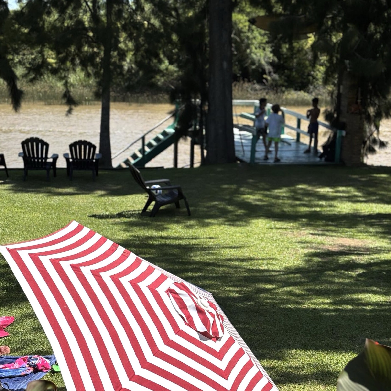 Muelle verde sobre el arroyo, jardín y sombrilla