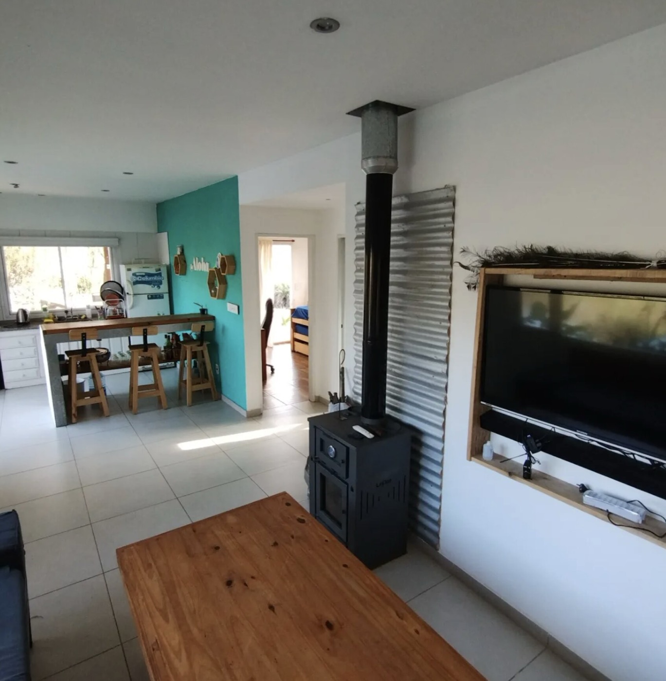 Living de Casa Maui con salamandra, barra de cocina y pasillo a los dormitorios