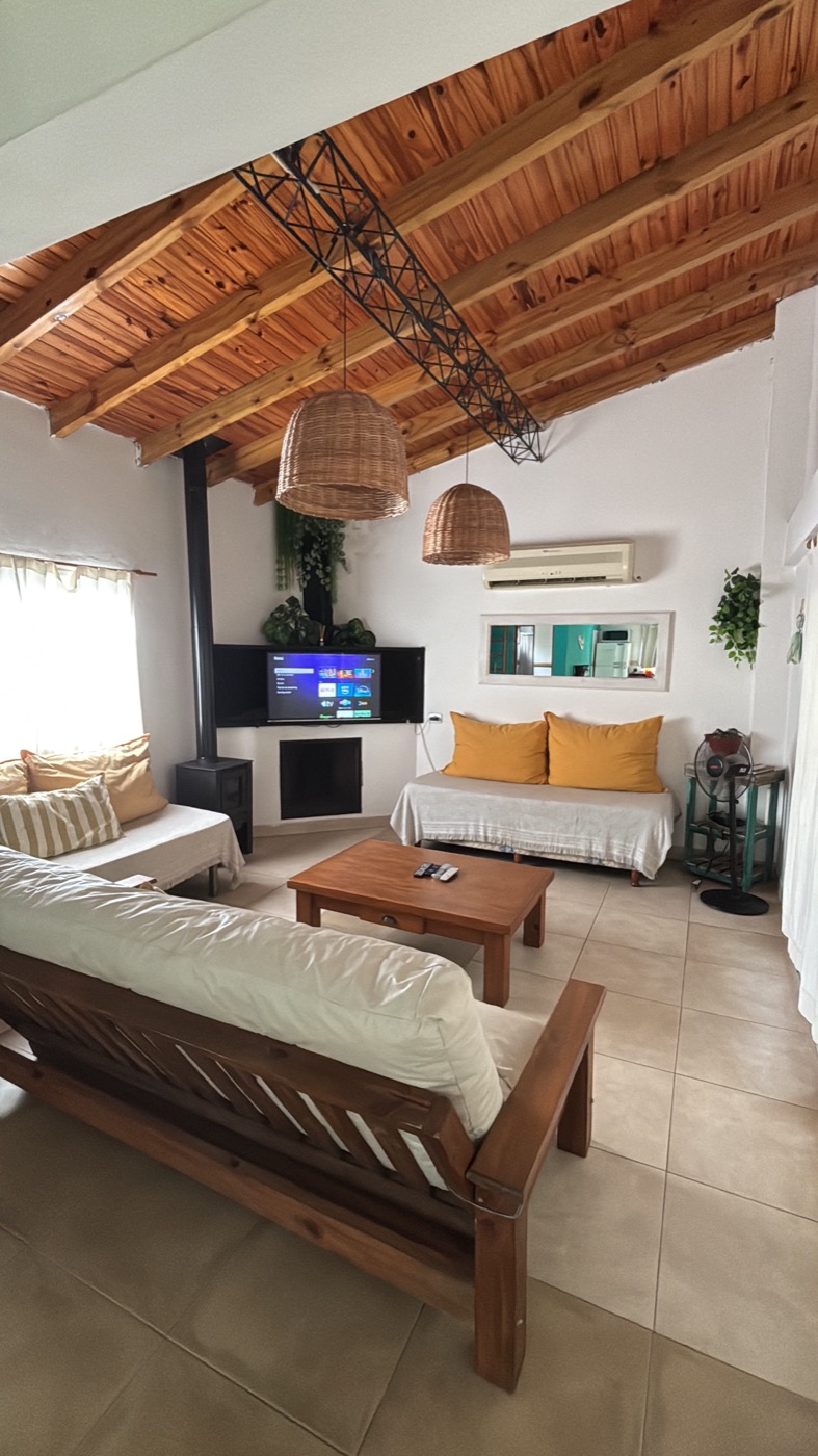 Living de Casa Pura Vida con salamandra, TV y techo de madera